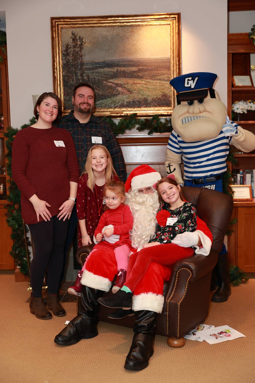 Parents and their three daughters sitting with Santa & Louie at the Holiday Brunch.
